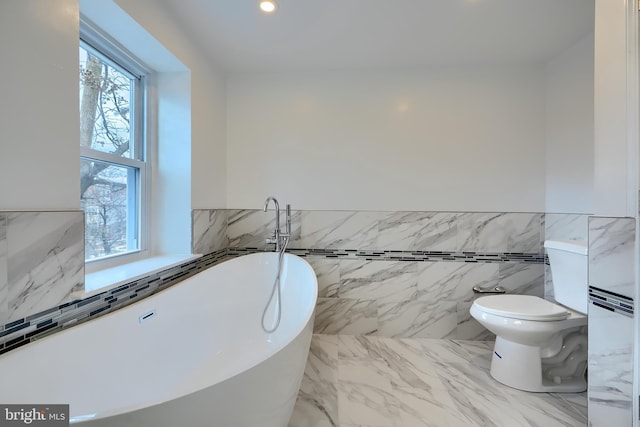 bathroom featuring tile walls, a wainscoted wall, toilet, a soaking tub, and recessed lighting