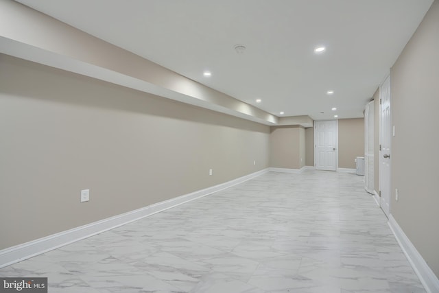 finished below grade area featuring baseboards, recessed lighting, and marble finish floor