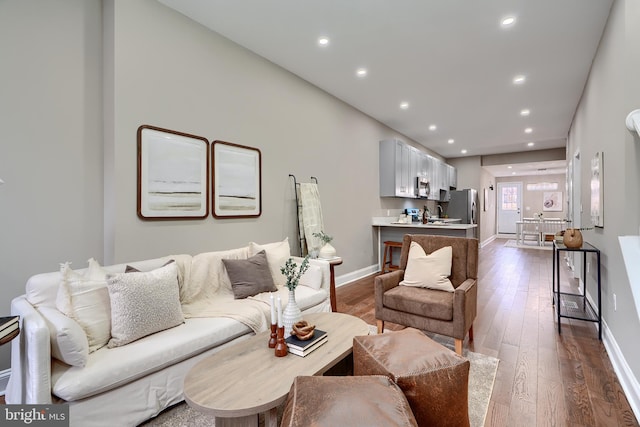 living area featuring baseboards, dark wood-style flooring, and recessed lighting