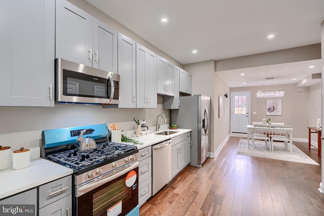 kitchen featuring light countertops, baseboards, appliances with stainless steel finishes, and a sink