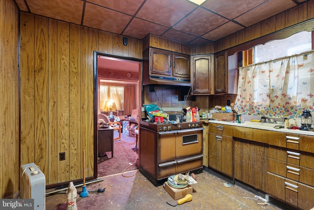 kitchen with under cabinet range hood, range with two ovens, and wood walls