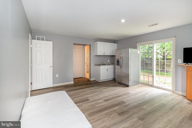 9116 Mineola Ct, Manassas, VA 20111 - kitchen featuring stainless steel fridge with ice dispenser, white cabinets, light wood-style floors, a sink, and baseboards
