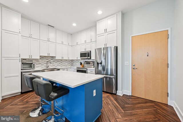 2772 Lighthouse Pt E Unit 410, Baltimore, MD 21224 - kitchen with stainless steel appliances, a kitchen bar, light countertops, white cabinetry, and backsplash