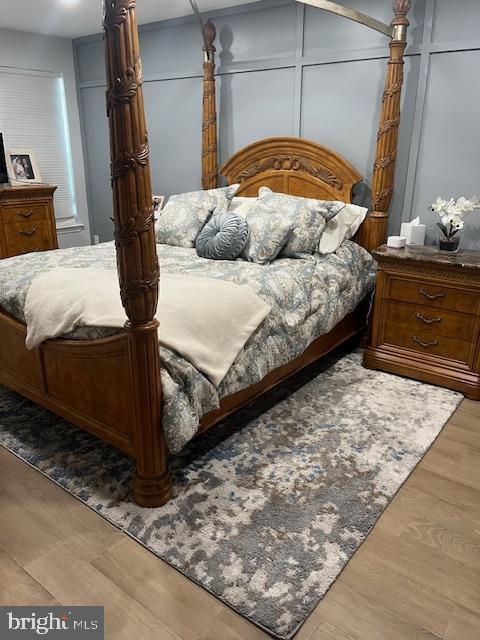 bedroom featuring wood finished floors and a decorative wall