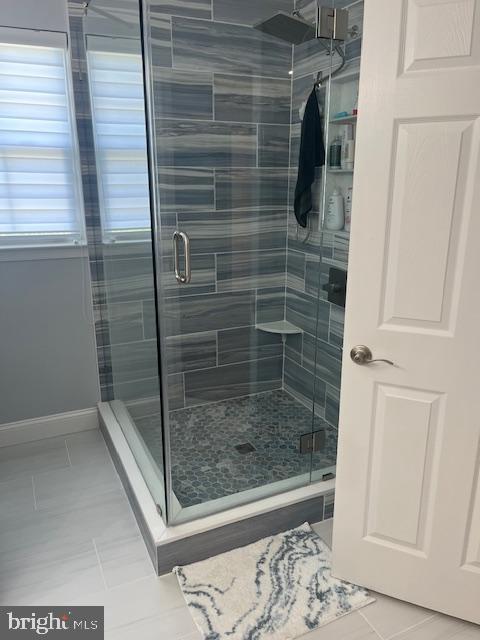 full bathroom with tile patterned flooring, baseboards, and a shower stall