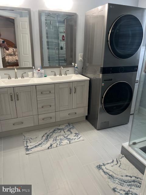 clothes washing area with stacked washer / drying machine and a sink