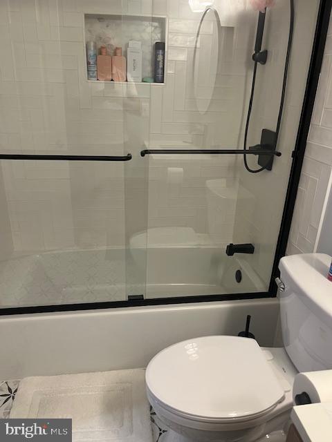 bathroom with enclosed tub / shower combo and toilet