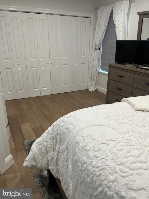 bedroom featuring baseboards, wood finished floors, and a closet