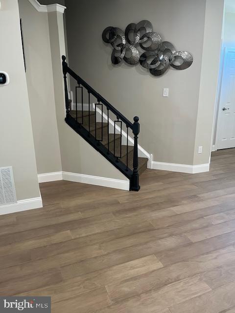stairs featuring an inviting chandelier, baseboards, wood finished floors, and visible vents