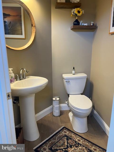 half bath featuring baseboards and toilet