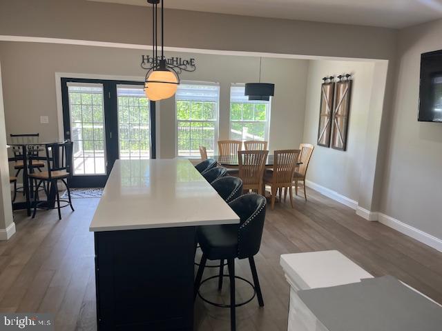 kitchen with baseboards, light countertops, wood finished floors, and a healthy amount of sunlight