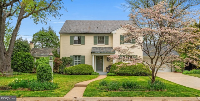 traditional home featuring driveway, a front yard, a high end roof, a garage, and brick siding