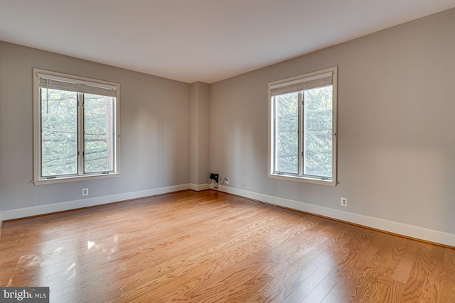 unfurnished room with plenty of natural light, wood finished floors, and baseboards
