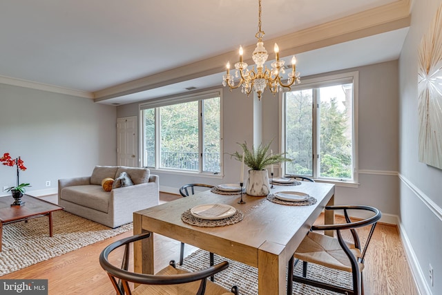 dining area featuring light wood finished floors, a chandelier, baseboards, and crown molding