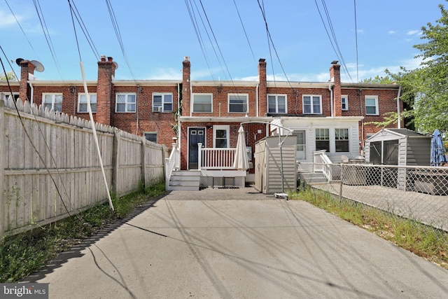view of front facade with fence, a storage unit, an outdoor structure, and brick siding