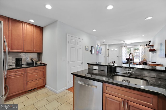 kitchen featuring decorative backsplash, recessed lighting, dark stone counters, a sink, and stainless steel appliances