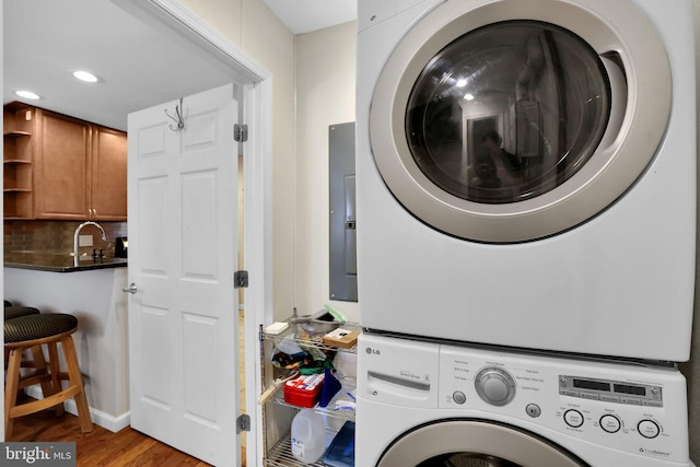 laundry area featuring stacked washing maching and dryer, laundry area, recessed lighting, and wood finished floors