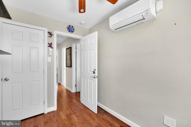unfurnished bedroom with baseboards, a wall unit AC, visible vents, and wood finished floors