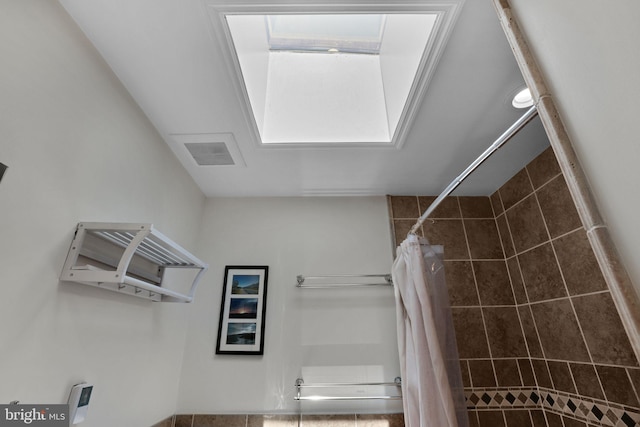 bathroom with a tile shower and visible vents