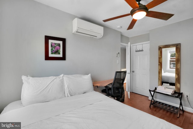 bedroom with a ceiling fan, a wall mounted air conditioner, wood finished floors, baseboards, and a closet