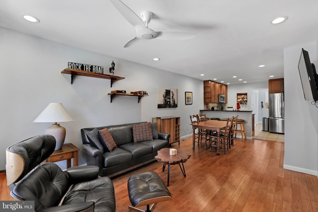 living area with baseboards, ceiling fan, recessed lighting, and light wood-style flooring