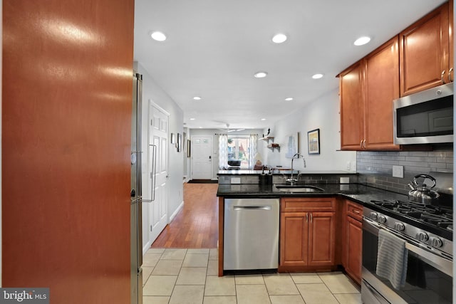 kitchen with recessed lighting, a sink, appliances with stainless steel finishes, and a peninsula