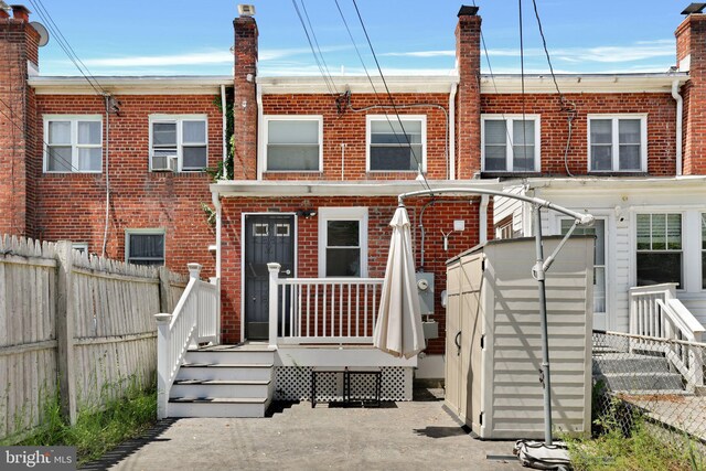 townhome / multi-family property with fence, a storage unit, an outdoor structure, and brick siding