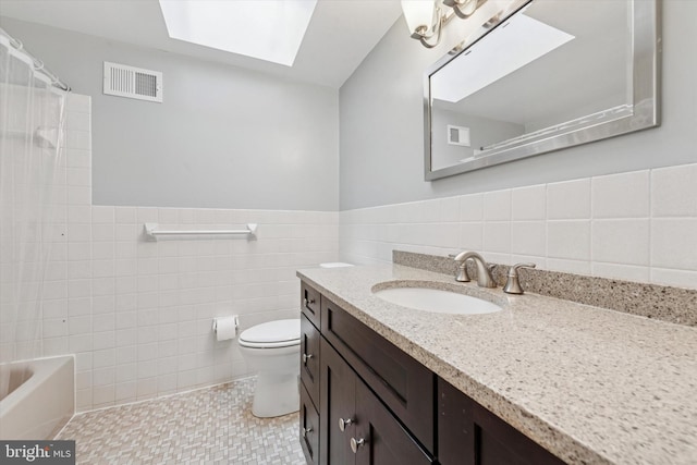 full bath featuring a shower with curtain, toilet, tile walls, a skylight, and visible vents