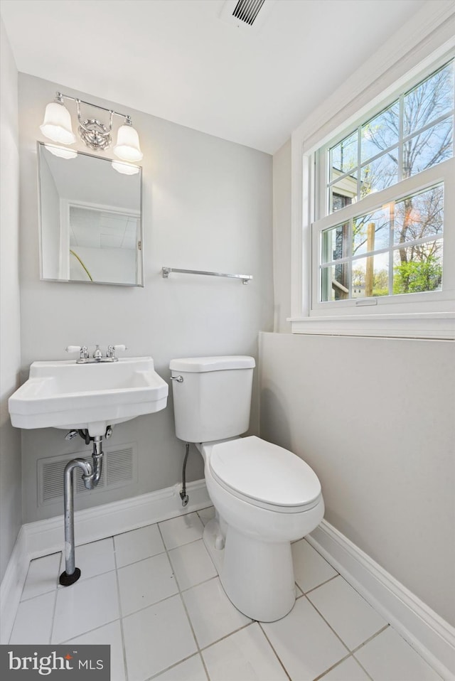 half bathroom featuring visible vents, tile patterned flooring, a sink, baseboards, and toilet