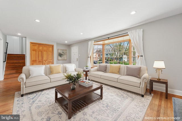 living area featuring recessed lighting, baseboards, stairway, and light wood-style floors