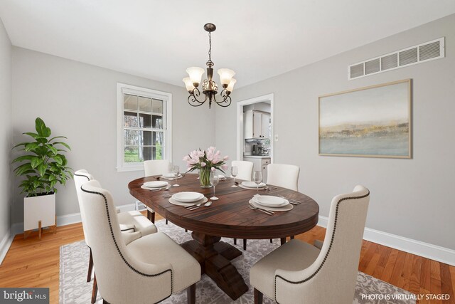 dining area featuring visible vents, light wood-style floors, baseboards, and a chandelier