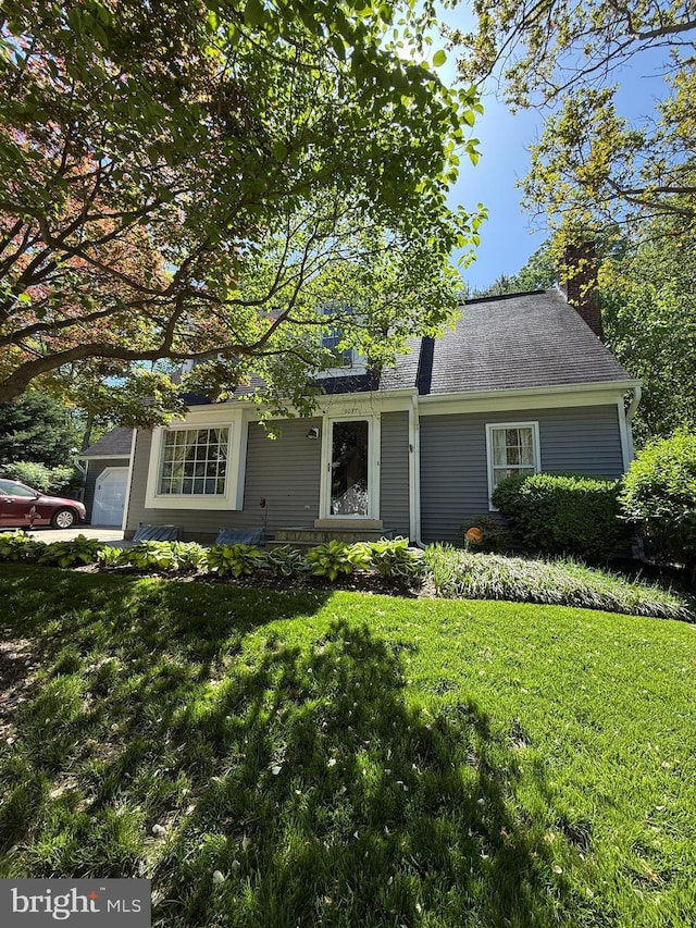 view of front of property with a chimney, a shingled roof, and a front yard