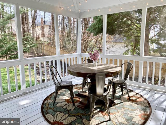 sunroom / solarium with a deck, wood-type flooring, and outdoor dining space