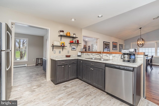 kitchen featuring a sink, light wood finished floors, stainless steel appliances, a peninsula, and a baseboard heating unit
