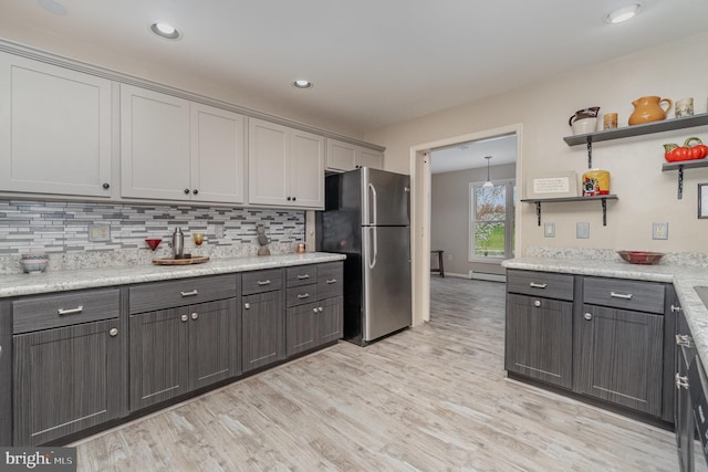 kitchen with freestanding refrigerator, backsplash, open shelves, and light wood finished floors