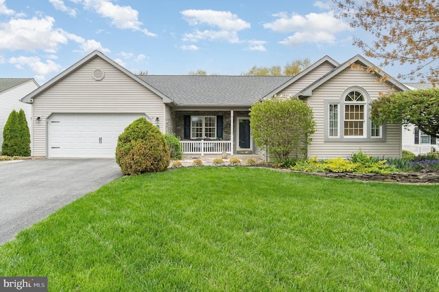 ranch-style house featuring covered porch, a front yard, aphalt driveway, an attached garage, and a shingled roof