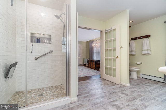 full bathroom with toilet, a baseboard heating unit, wood finished floors, and a stall shower