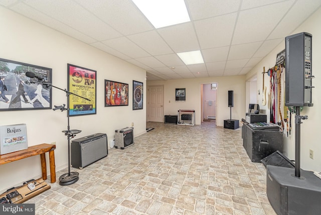 interior space featuring baseboards, brick floor, and a drop ceiling