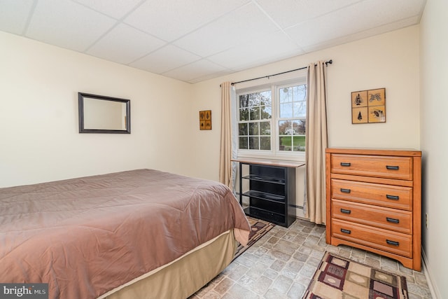 bedroom with a paneled ceiling and stone finish floor