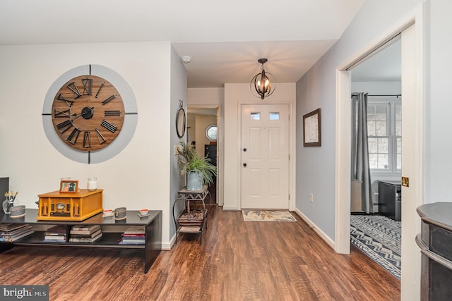 foyer with baseboards, a chandelier, and wood finished floors
