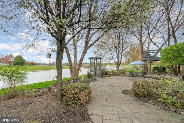 view of property's community featuring a yard, a water view, and a patio area