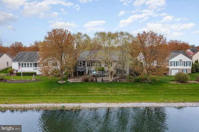 back of property with a lawn, a water view, and a patio