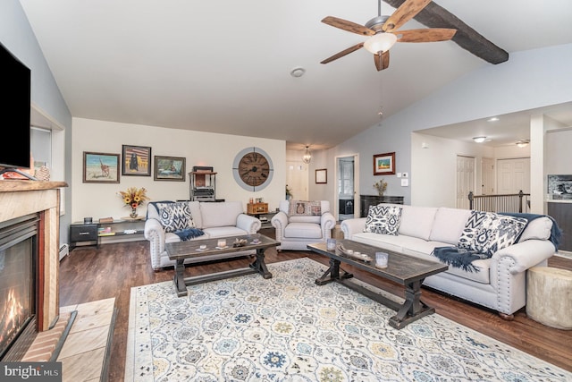 living area with ceiling fan, vaulted ceiling with beams, a glass covered fireplace, and wood finished floors