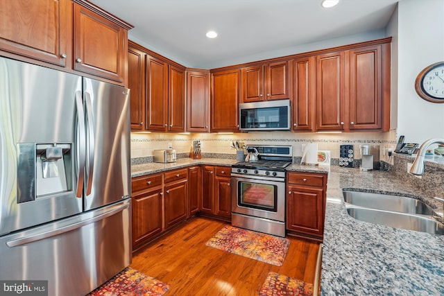 44451 Cruden Bay Dr, Ashburn, VA 20147 - kitchen featuring appliances with stainless steel finishes, wood finished floors, a sink, light stone counters, and recessed lighting