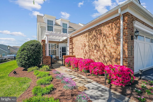 44451 Cruden Bay Dr, Ashburn, VA 20147 - view of side of property featuring a gate, a pergola, an attached garage, and brick siding