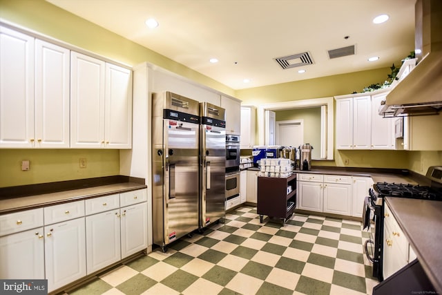 44451 Cruden Bay Dr, Ashburn, VA 20147 - kitchen with wall chimney range hood, dark countertops, stainless steel appliances, light floors, and visible vents