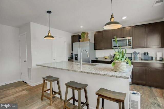 11174 Cross Fields Dr, Waynesboro, PA 17268 - kitchen featuring dark brown cabinets, light wood-style floors, baseboards, a kitchen breakfast bar, and stainless steel appliances