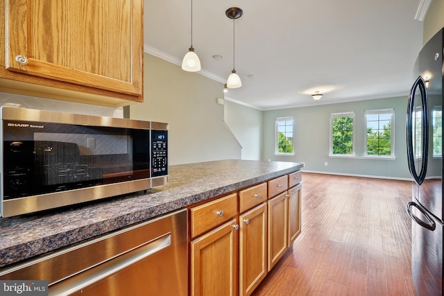 22788 Sagamore Sq, Brambleton, VA 20148 - kitchen featuring dark countertops, ornamental molding, light wood-style flooring, and appliances with stainless steel finishes