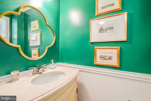 bathroom featuring a wainscoted wall, vanity, and a decorative wall