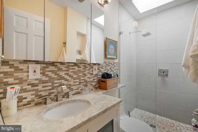 full bathroom featuring vanity, backsplash, a skylight, and tiled shower